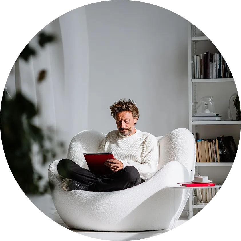 dojrzały mężczyzna siedzi na białym fotelu i coś czyta