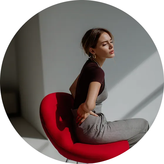 kobieta siedzi na fotelu i trzyma się za biodra