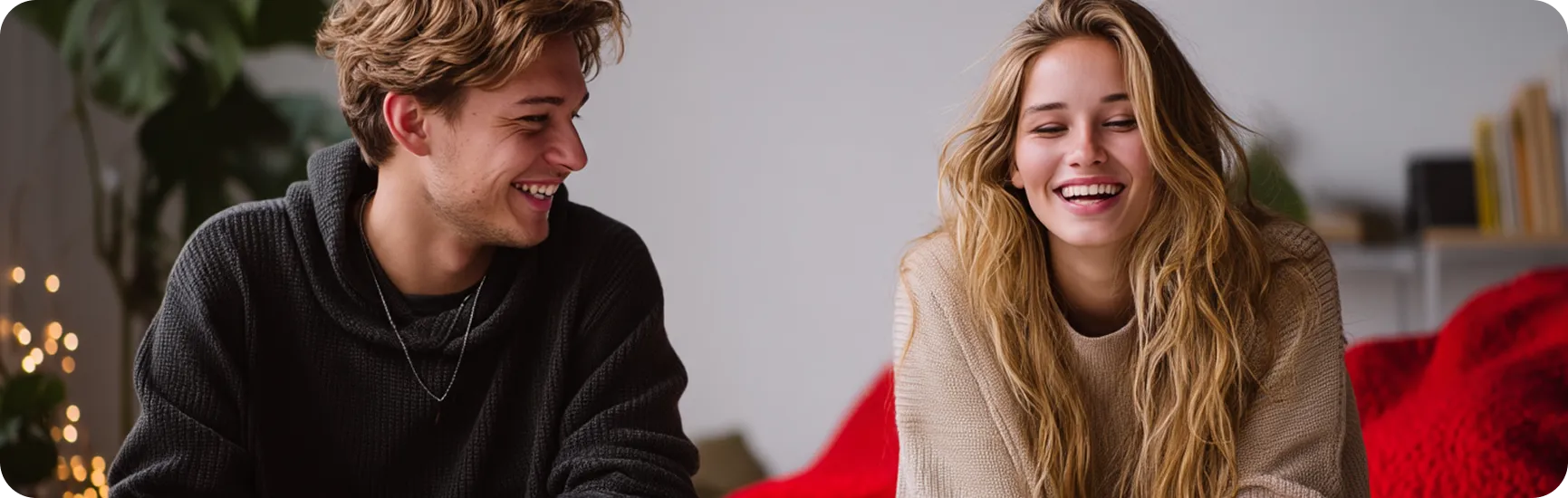 chłopak blondyn w czarnym swetrze i dziewczyna blondynka w białym swetrze uśmiechają się do siebie